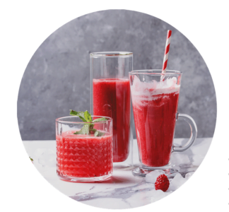 Three glasses of red fruit juice, inspired by smoothie recipes, sit on a marble surface—one with a straw, another with mint garnish, all surrounded by ice cubes and fresh raspberries.