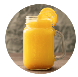 A mason jar filled with orange juice, inspired by classic smoothie recipes, is garnished with a slice of orange on the rim and sits on a wooden surface.