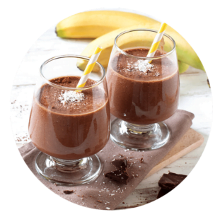 Two glasses of chocolate smoothie with yellow striped straws, garnished with coconut flakes, sit on a napkin with banana and chocolate pieces in the background—an irresistible treat for anyone searching for new smoothie recipes.